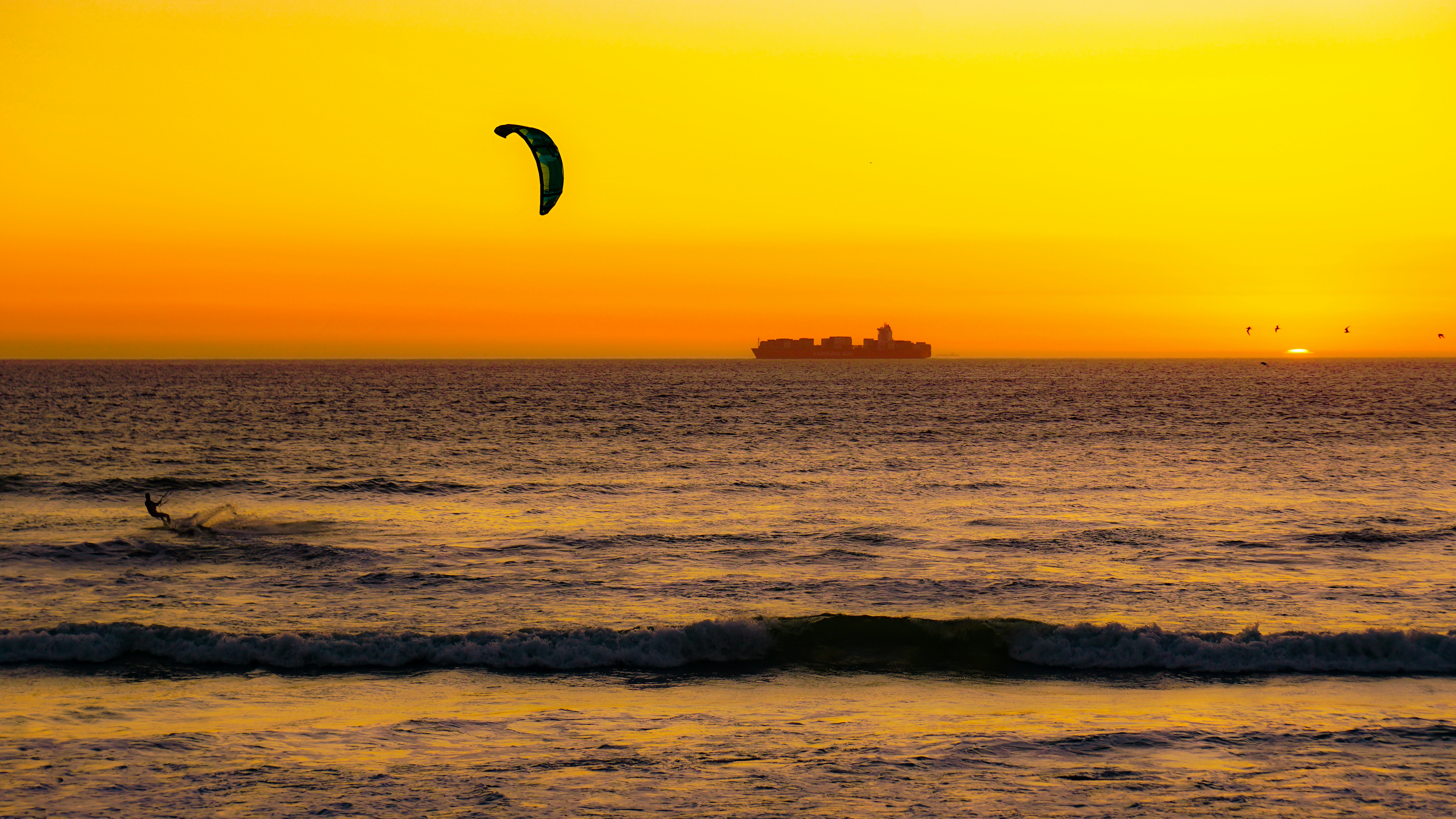 Persona surfeando sobre las olas del mar durante la puesta de sol