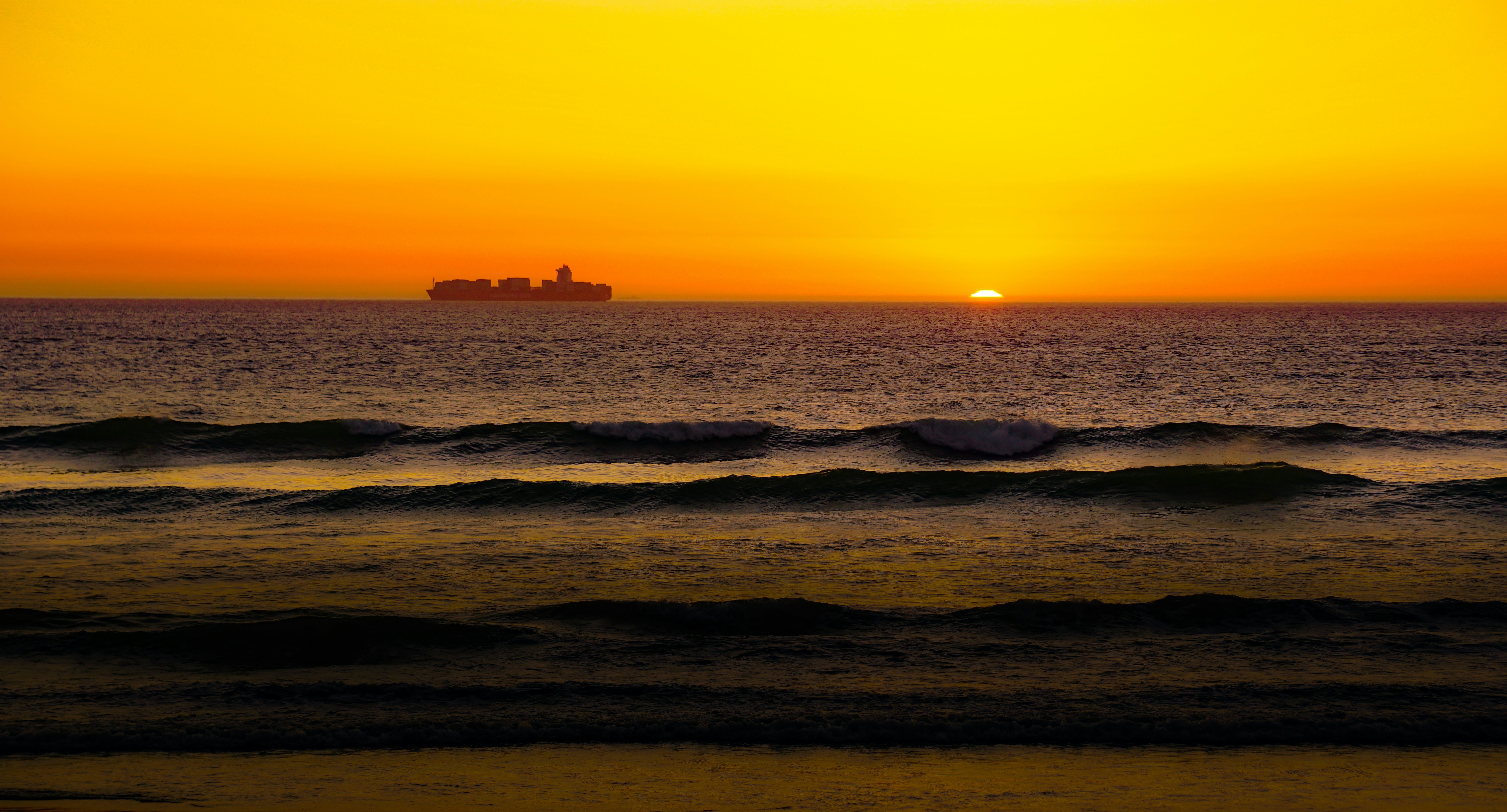 Olas del océano rompiendo en la costa durante la puesta de sol