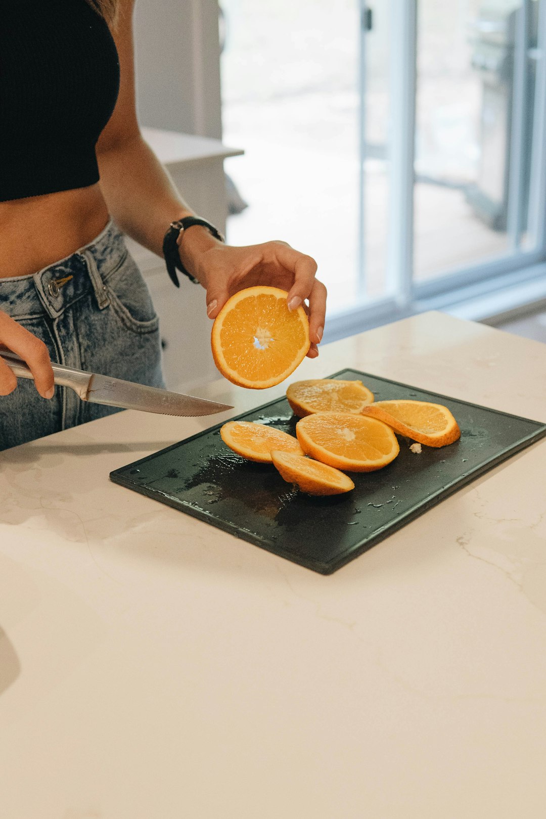 person slicing orange fruit on chopping board