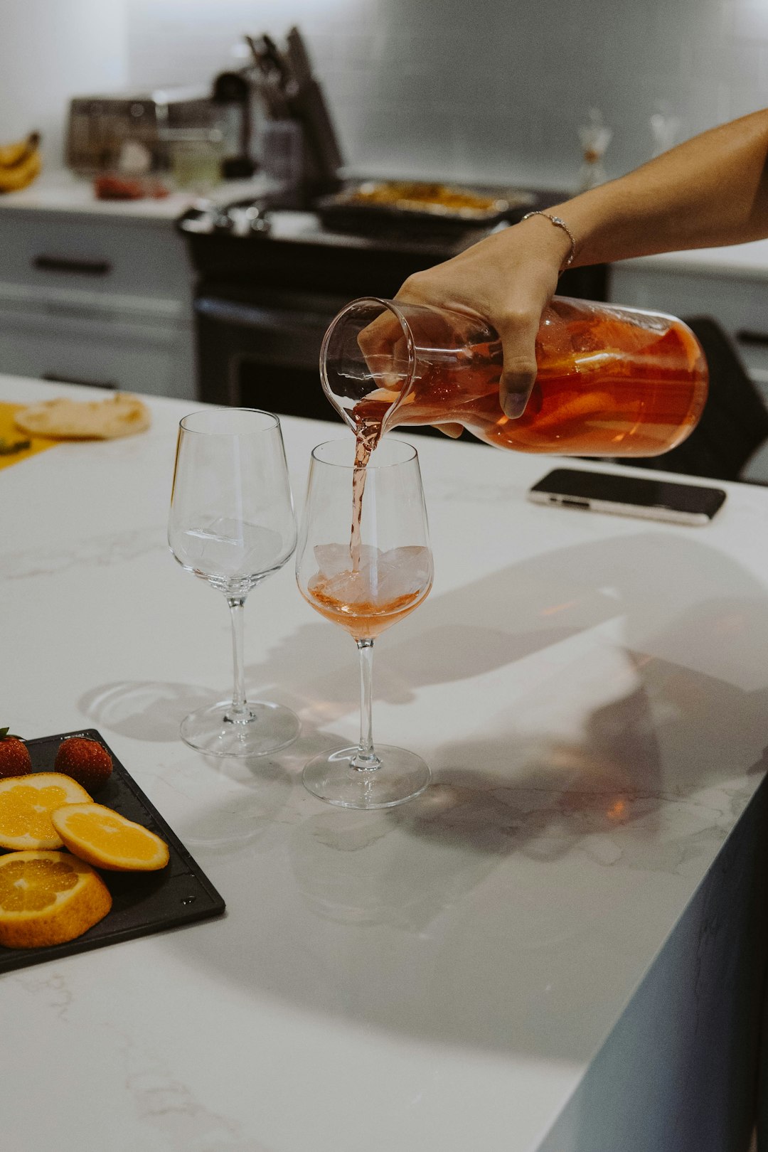 person pouring brown liquid on clear wine glass