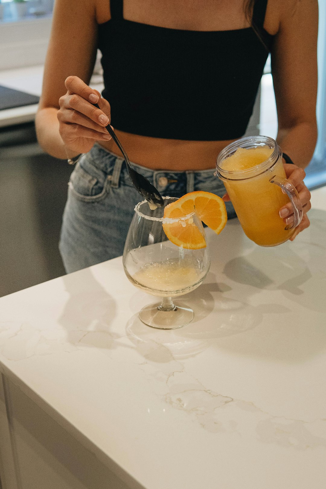 woman in black tank top holding silver spoon and clear drinking glass