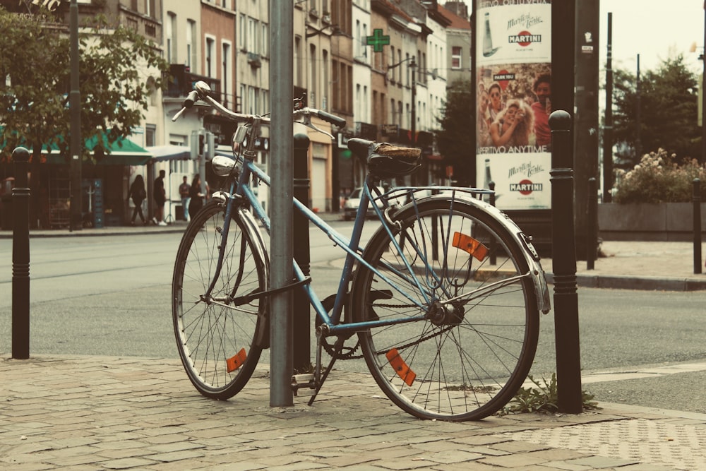 blue city bike parked beside black metal fence during daytime