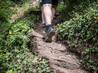 A man wearing vibrant sandals while hiking on a scenic trail surrounded by greenery.