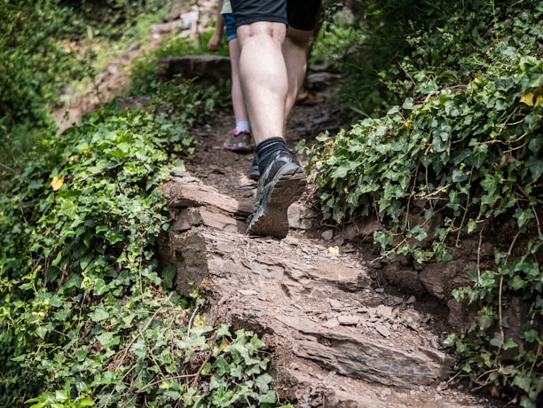 A man wearing vibrant sandals while hiking on a scenic trail surrounded by greenery.