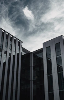 Cinematic shot of a sleek commercial building exterior with matte black and gold accents under a dramatic sky