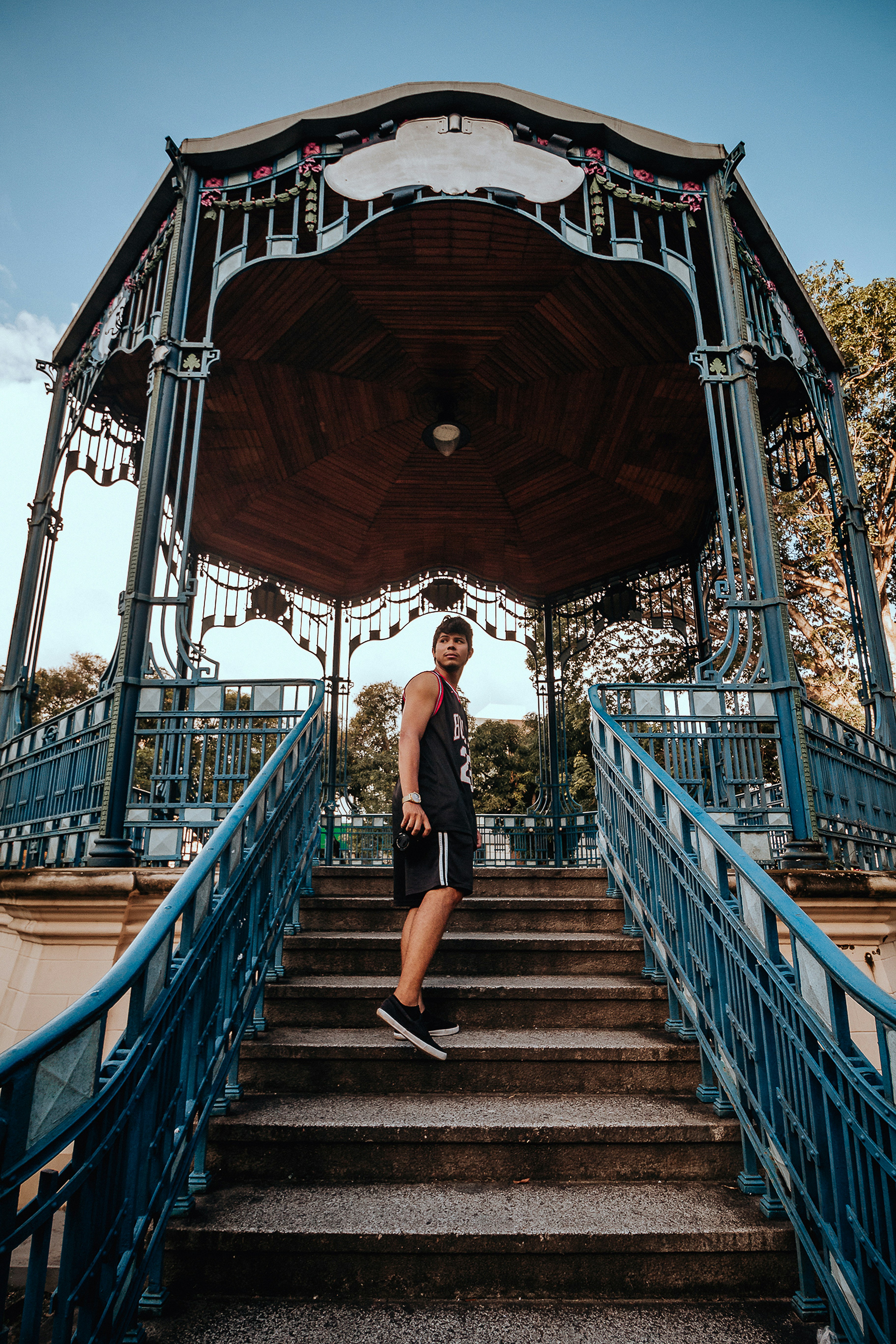 woman in black tank top and black pants walking on brown wooden bridge during daytime