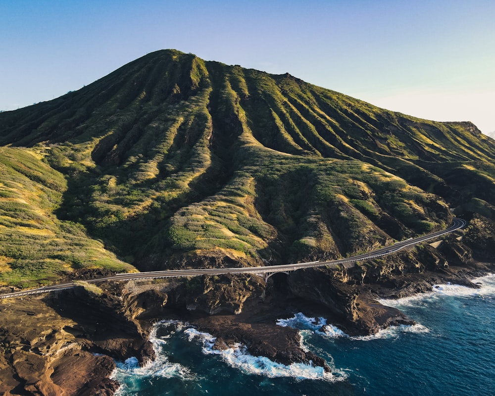 green and brown mountain beside sea during daytime