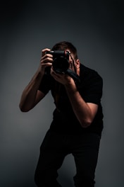 man in black t-shirt holding black dslr camera