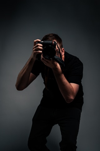 man in black t-shirt holding black dslr camera