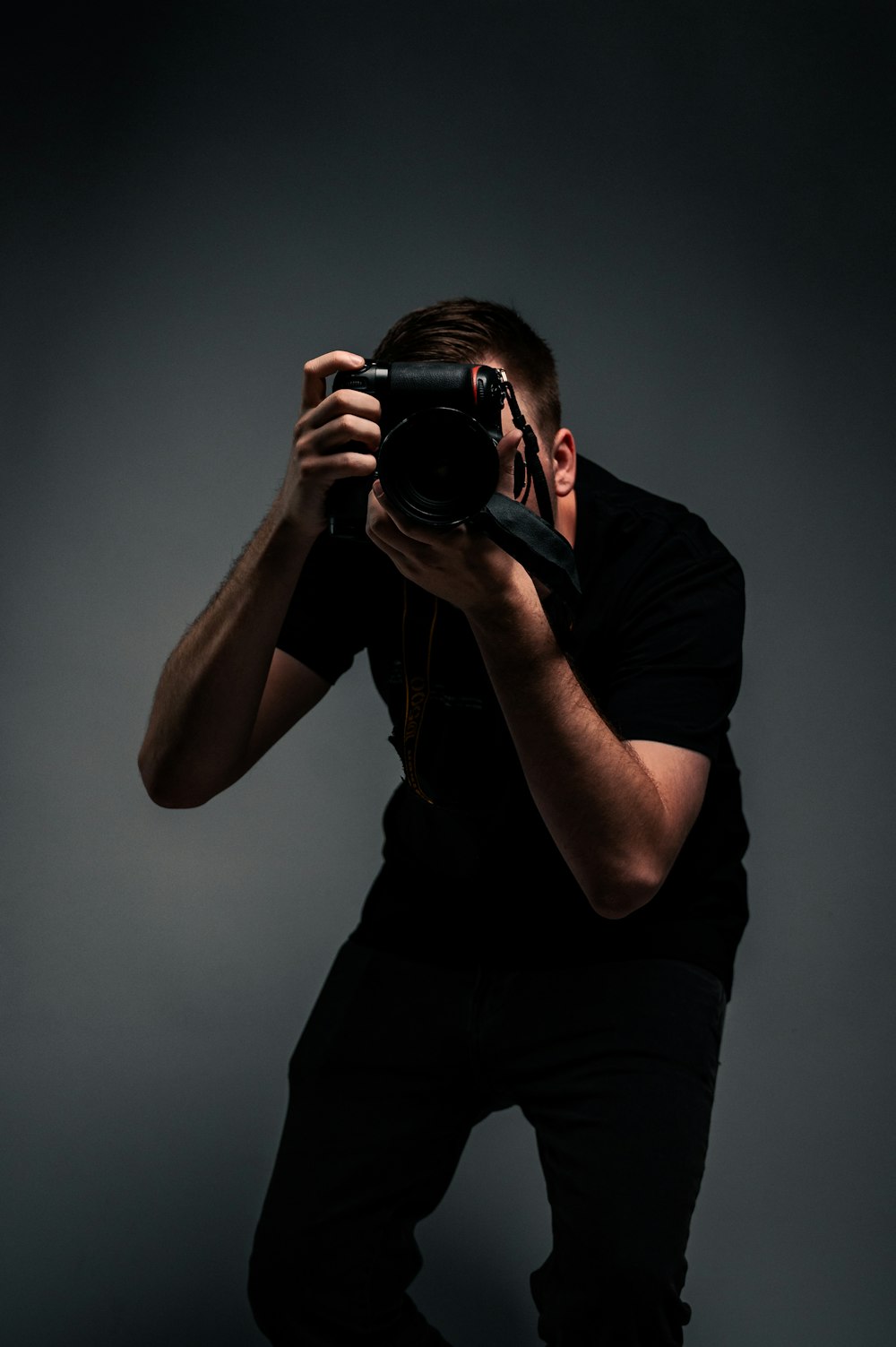 man in black t-shirt holding black dslr camera