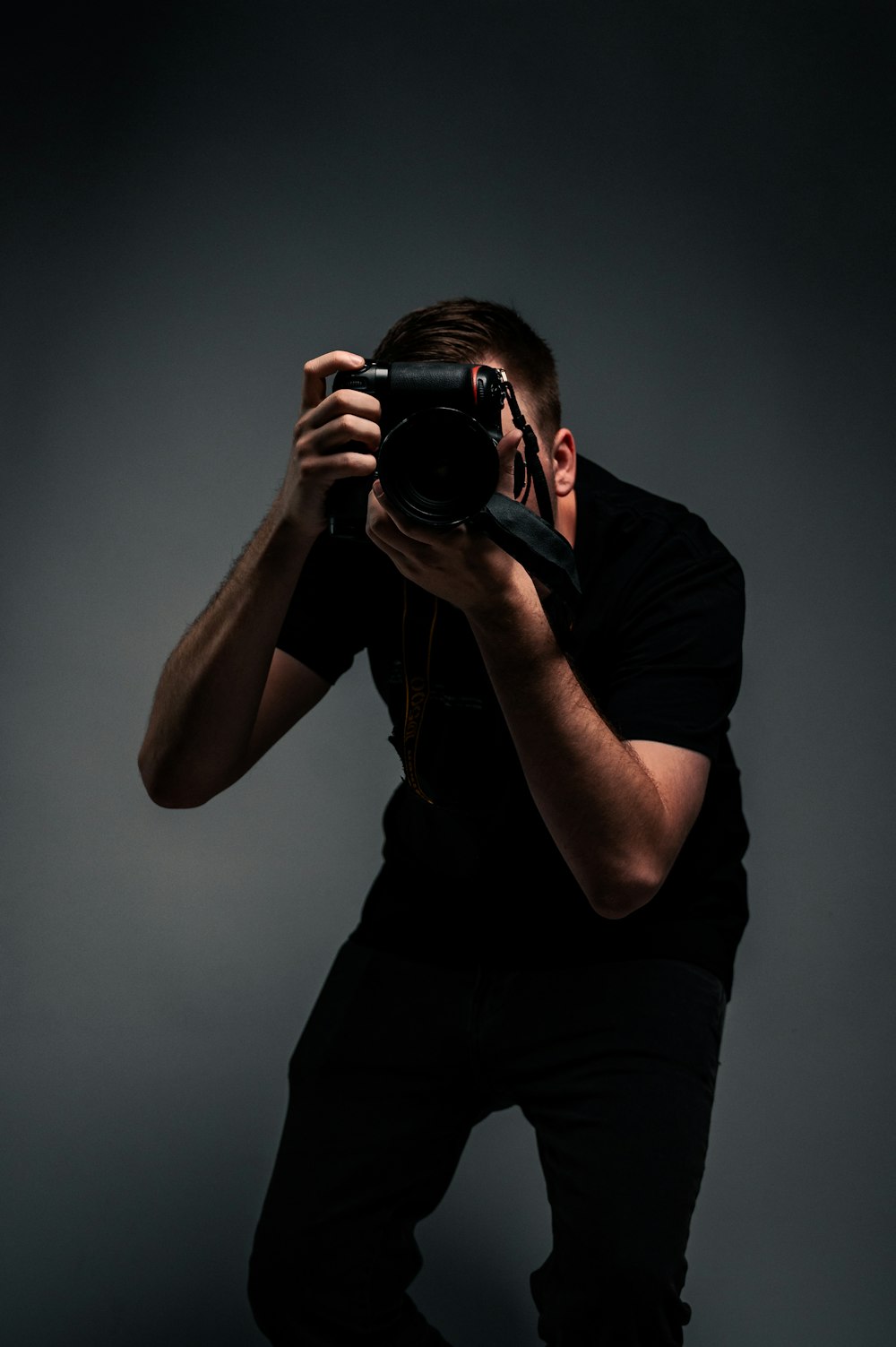 Hombre con camiseta negra sosteniendo una cámara DSLR negra