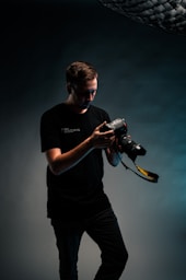man in black crew neck t-shirt holding black dslr camera