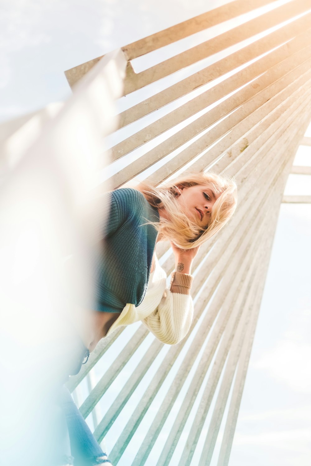 woman in blue sweater leaning on white wall