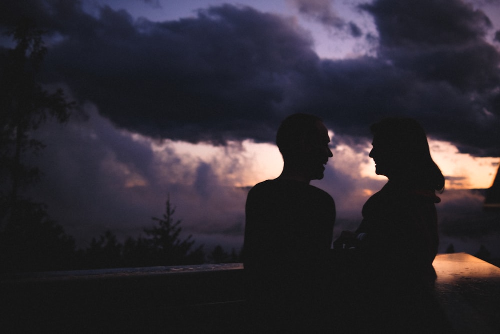 silhouette of 2 person standing on road during night time