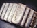 A collection of silver bars from Wall Street Mint, each bar displaying detailed engravings, including the name, weight, and purity of the silver. The bars are arranged in a slight diagonal line and feature a reflective, polished surface.