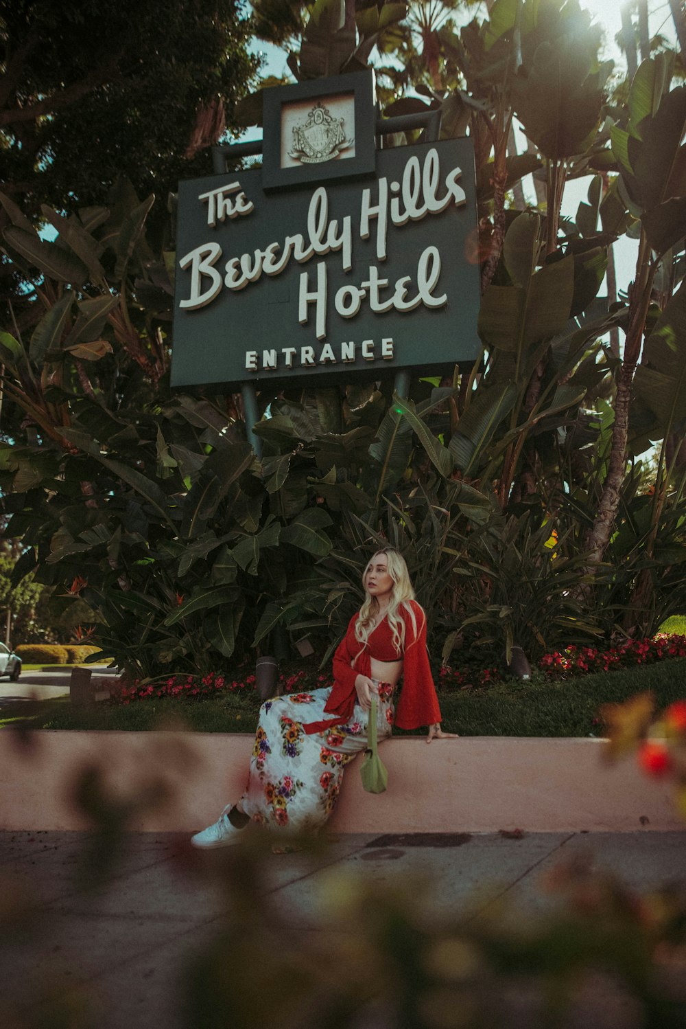 woman in red and white floral dress sitting on brown concrete bench