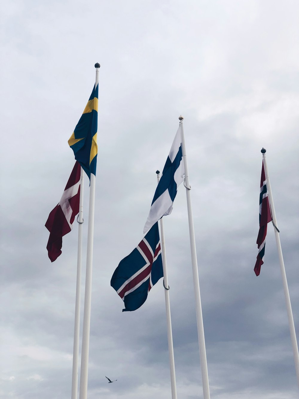 three flags on white pole during daytime