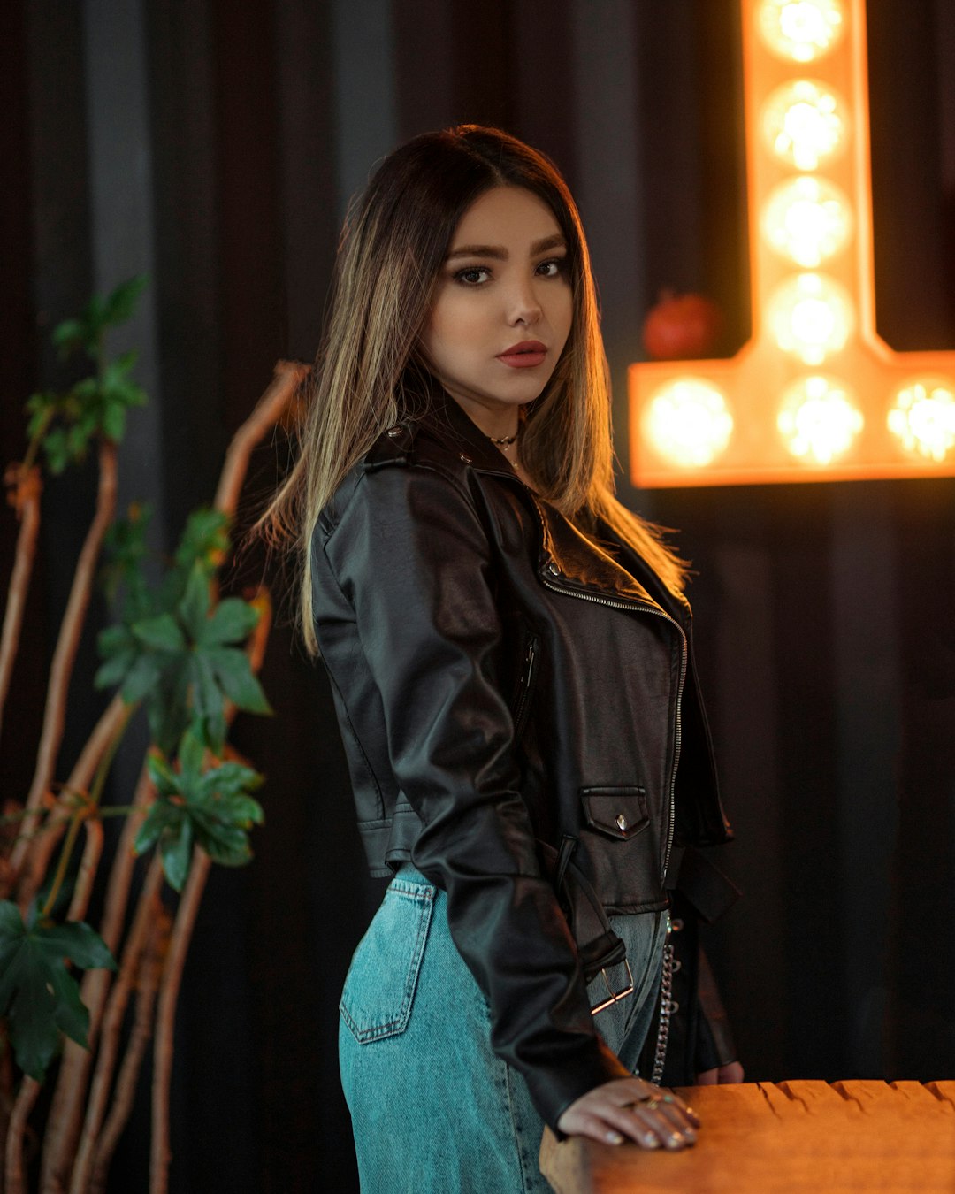 woman in black leather jacket standing near green plant during daytime