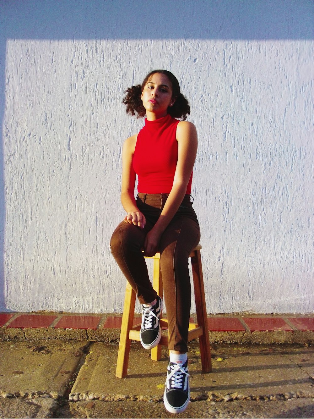 woman in red tank top and black leggings sitting on brown wooden seat