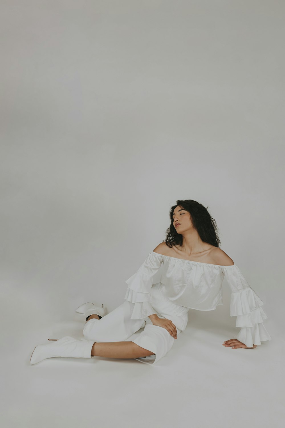 donna in vestito bianco che si siede sul pavimento bianco