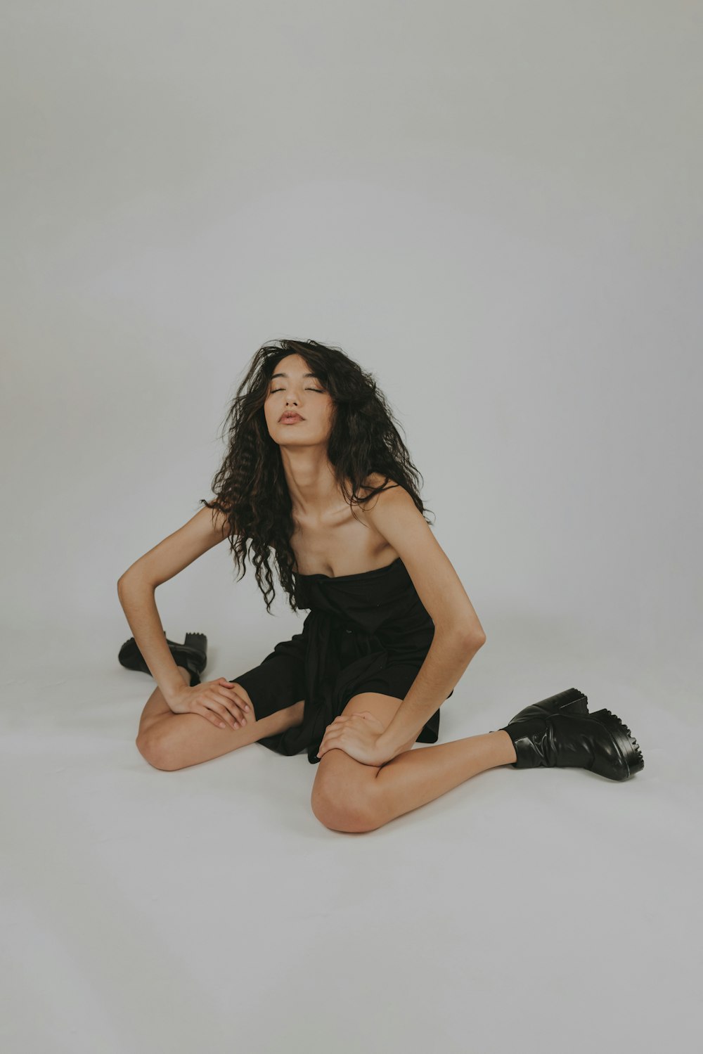 woman in black spaghetti strap dress sitting on white floor