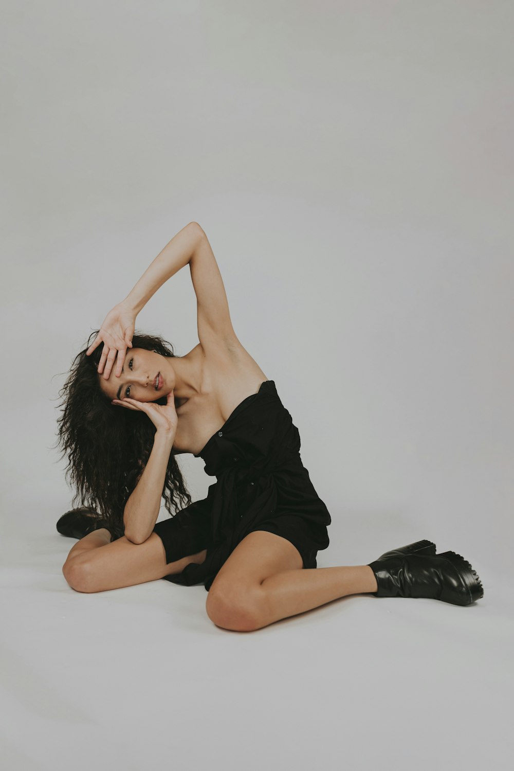 woman in black dress lying on white floor