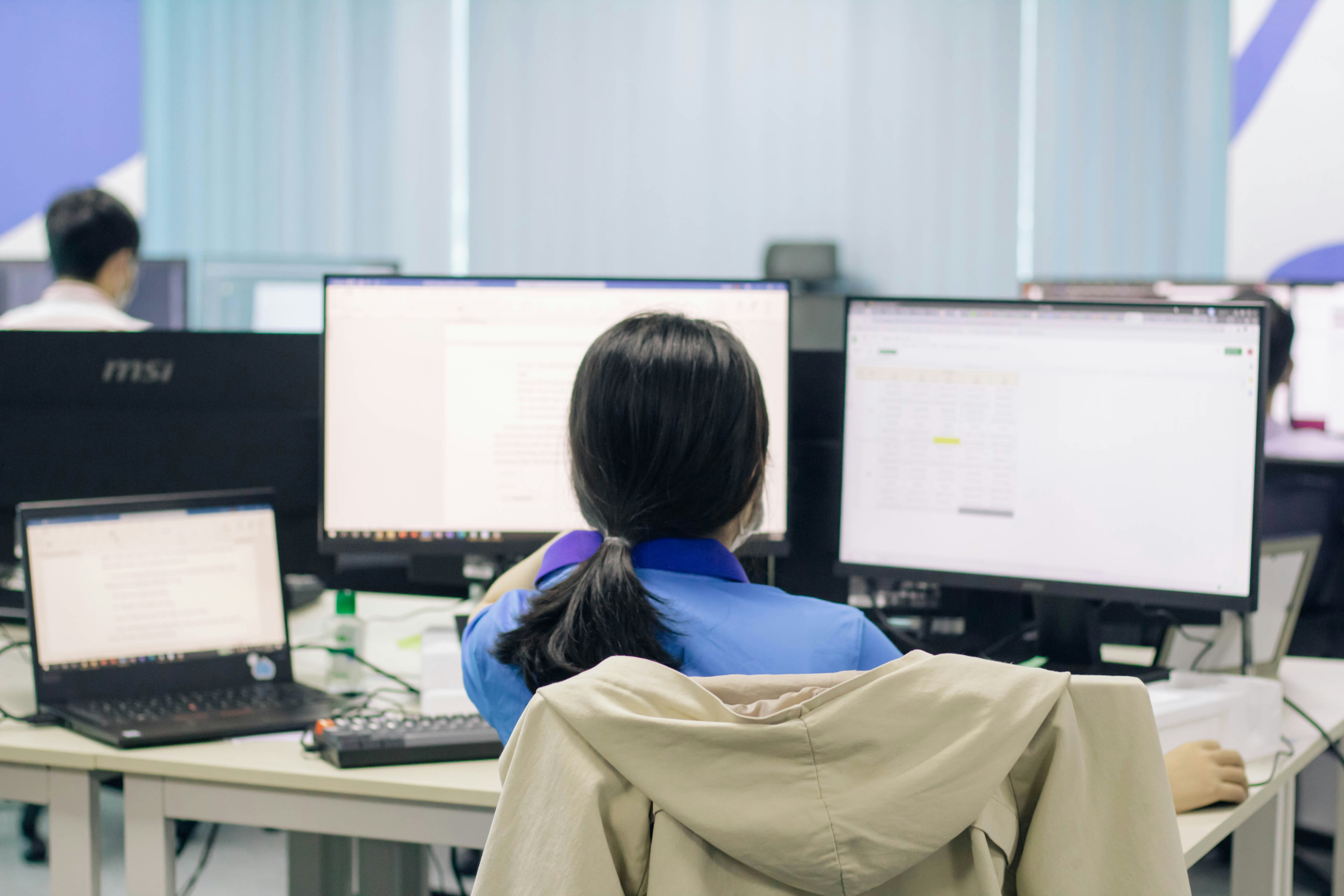 Woman in blue shirt sitting on chair in front of computer
