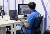boy in blue t-shirt sitting on black office rolling chair in front of computer