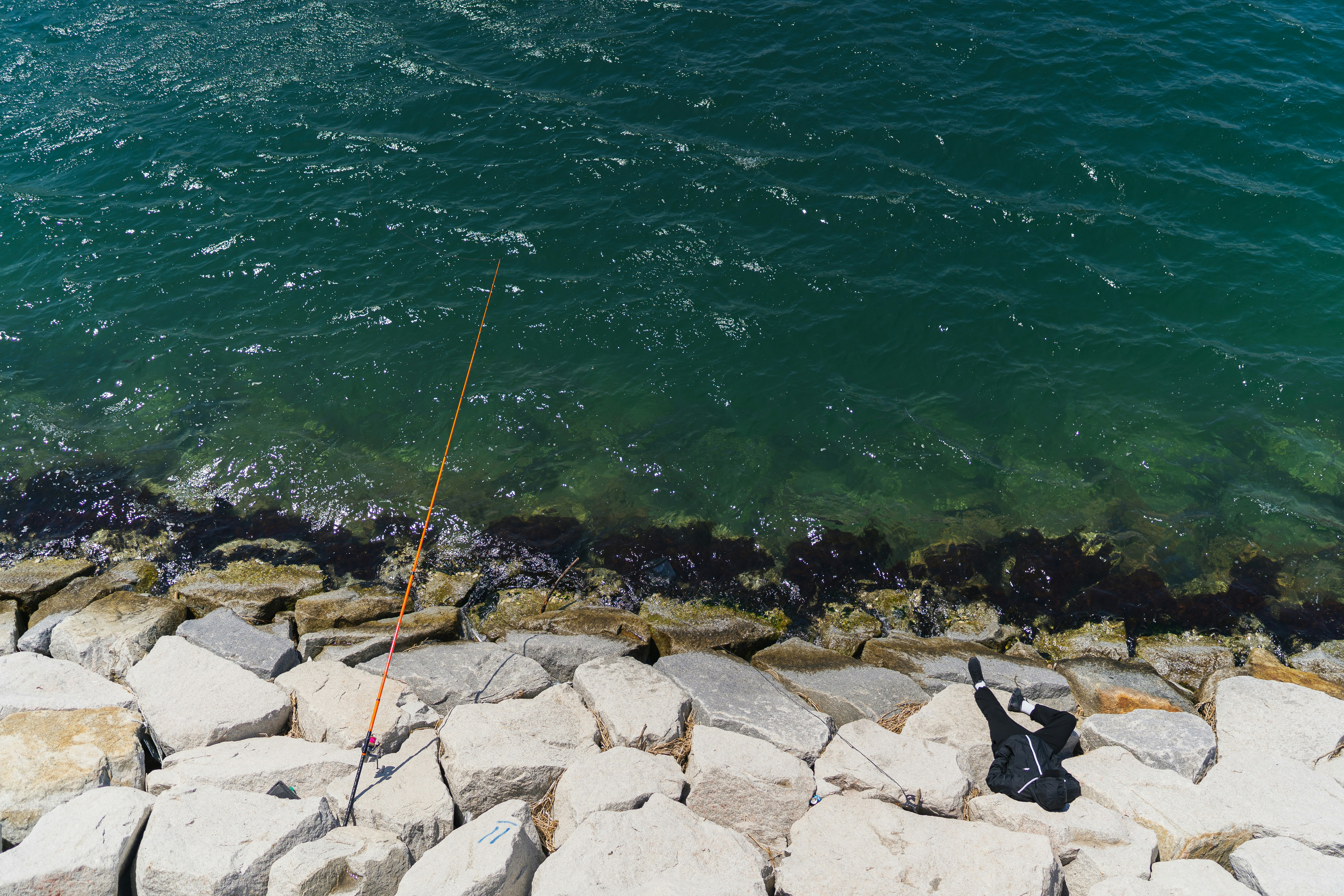 gray rocks beside body of water during daytime