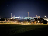 A well-lit municipal sports field at dusk with LED lights glowing warmly.