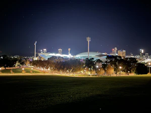 A vibrant stadium lit up at dusk with athletes preparing for a corporate sports event.