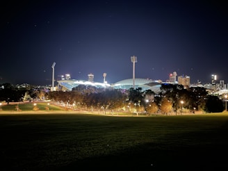 A moody stadium under neon green floodlights with a bold sans-serif scoreboard glowing in the dark.