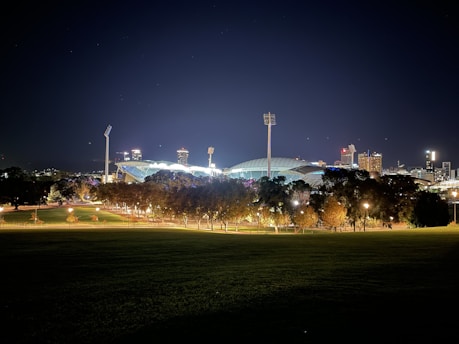 A moody stadium under neon green floodlights with a bold sans-serif scoreboard glowing in the dark.