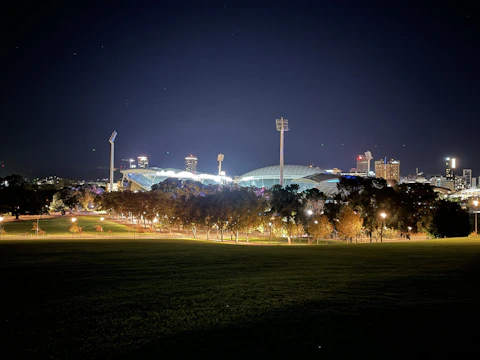 A well-lit municipal sports field at dusk with LED lights glowing warmly.