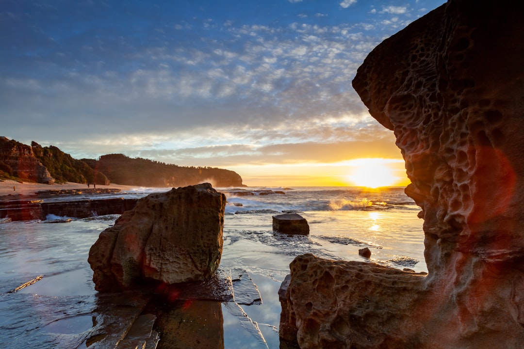 brown rock formation on sea shore during sunset