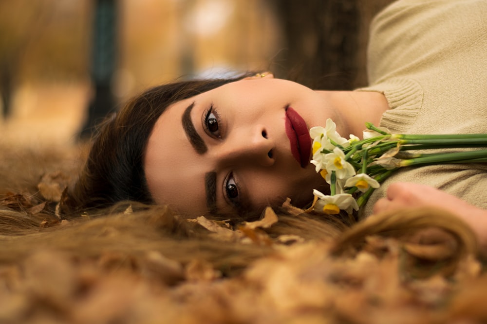 woman in beige shirt lying on dried leaves