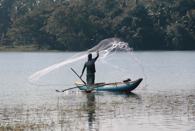 A man showing a fishing technique on a serene lake, with eager learners watching closely.