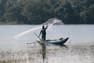 man in black long sleeve shirt riding on blue kayak on lake during daytime