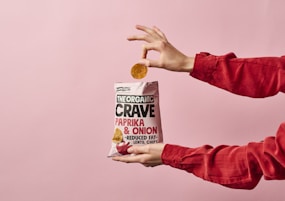 person holding white and red plastic pack