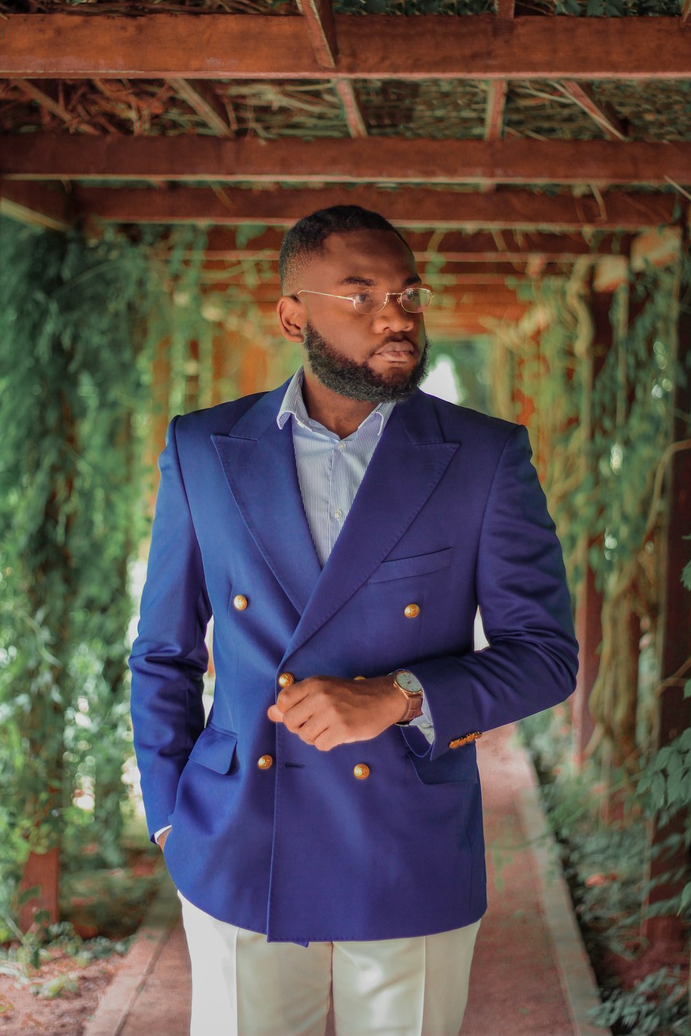 man in blue suit jacket standing near brown wooden wall