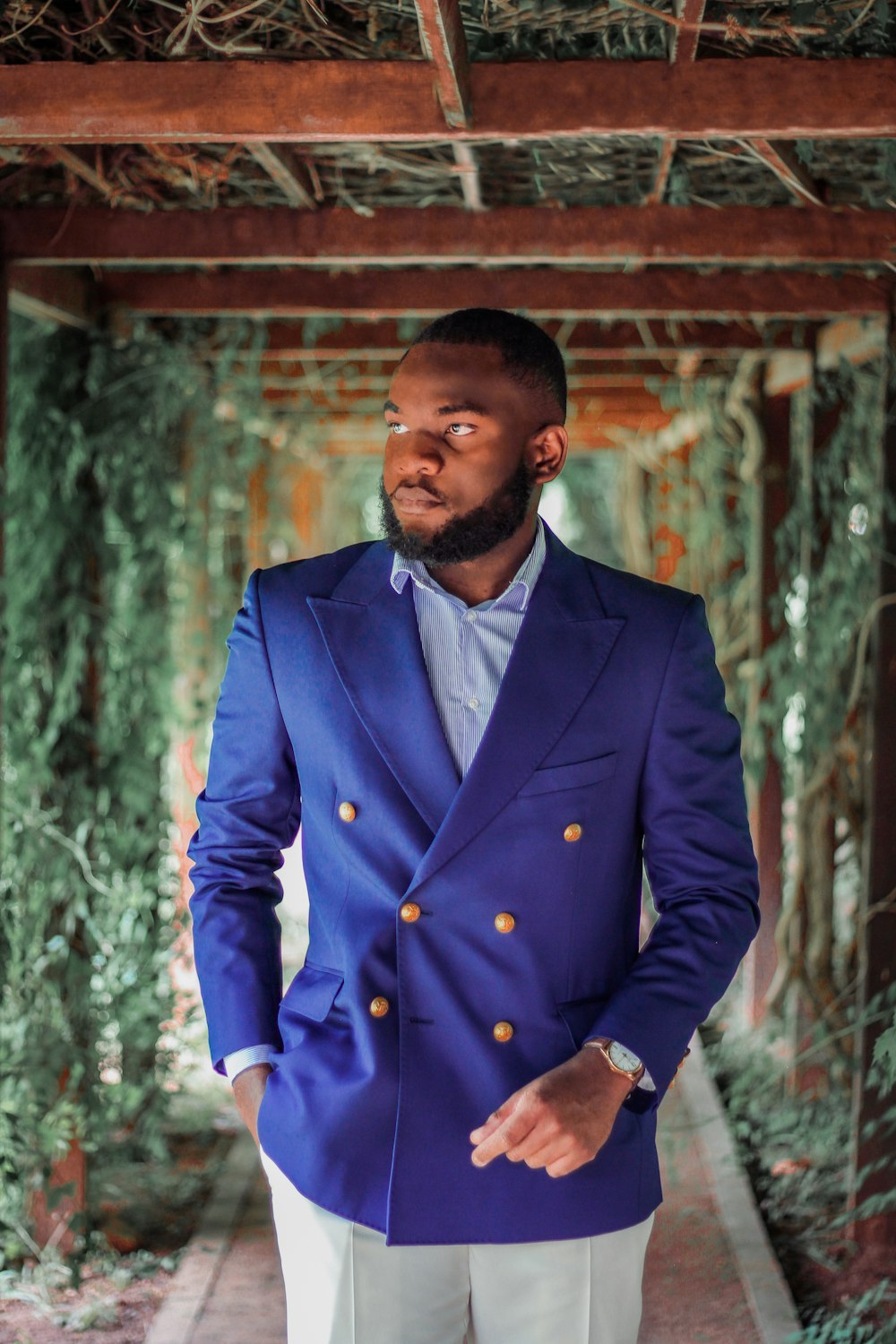 man in blue suit standing near brown wooden wall