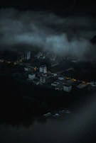 An abandoned, fog-covered village with dim purple lights in the windows.