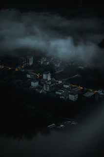 An abandoned, fog-covered village with dim purple lights in the windows.