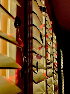 A sunlit windowsill displaying a row of small, cheerful ceramic hearts in various bright glazes.