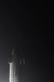 A sleek rocket being carefully loaded onto a modern transport truck at sunset.