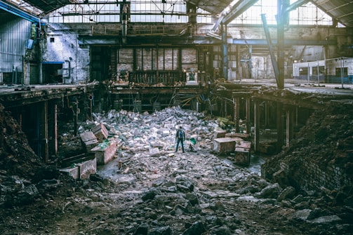 A wide shot of a person standing thoughtfully in a reclaimed industrial area.