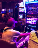 man in white t-shirt playing arcade game