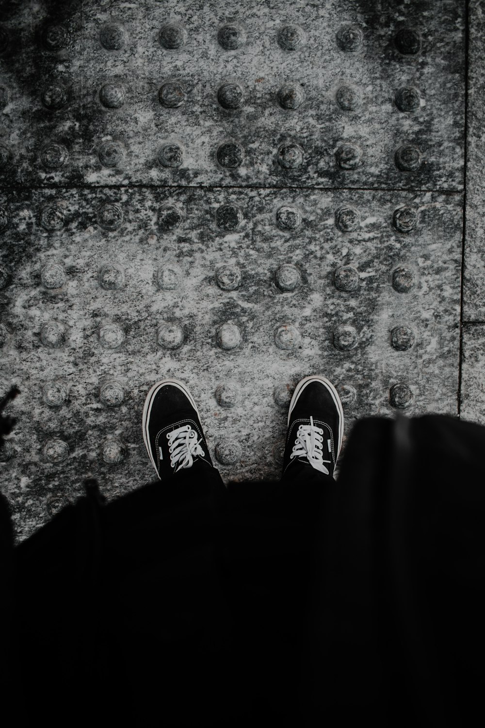 person in black pants and black and white sneakers