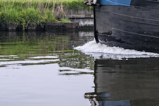 Close-up of a robust rib hull slicing through calm river waters with a motorboat in the background.