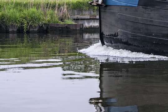 Close-up of a robust rib hull slicing through calm river waters with a motorboat in the background.